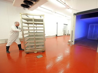 Man pushing commercial food trolley into cool room 