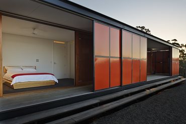 M+A surrounded the living core of the 76sqm house with an operable exterior shell of highly visible, red and orange exterior panels. Photography by Peter Whyte