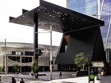 The canopy, positioned on a concrete-filled steel column cantilevers out into the street, sheltering both the plaza and the building