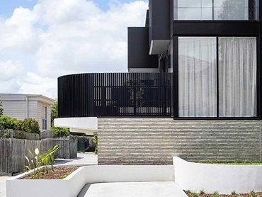 The muted palette is led by handmade Petersen Kolumba (K91) bricks, along with black aluminium cladding and white render