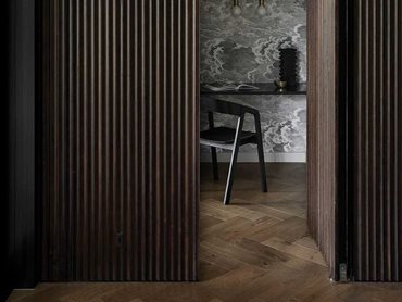 The lighter herringbone timber floor is a perfect match for the darker fluted timber lining on the walls