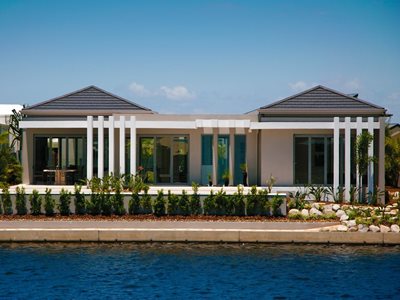 External view of modern home with concrete roof tiles overlooking water