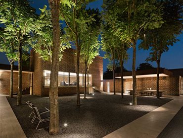 The studio is arranged as a cluster of buildings around a central courtyard featuring several trees 