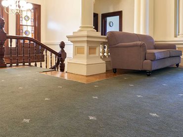 The custom woven carpet took inspiration from the gothic revival architecture era, featuring a repeat pattern of stylised Fleur-de-lis on a lush green base