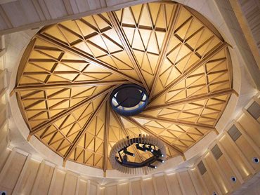 The ceiling design features timber and steel composite beams interlocking at the crown