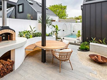 Staggered Newham pavers are laid beneath the outdoor dining setting adjacent to the wood-fired pizza oven