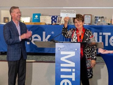 MiTek Chairman and CEO Mark Thom watches as Marie Jureit-Beamish holds the original Gang-Nail connector plate 