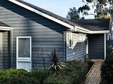 The exterior features freshly painted charcoal-coloured weatherboards