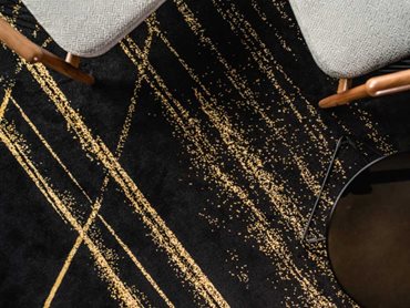 The carpet's charcoal base provides the perfect platform for the sparkling gold highlight