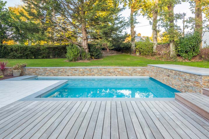 inground swimming pool with deck garden green