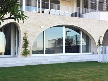 Three large irregular brick arches span from one side of the home to the other, accommodating the openings