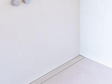 Lauxes Grates' slimline tile insert grates are featured in the minimalist marble bathrooms 