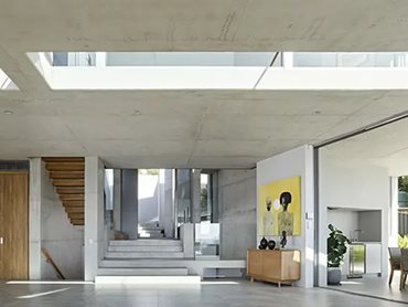 The ceiling of this main living area is off-form concrete and features a central glazed void that bathes the interior in even more natural light