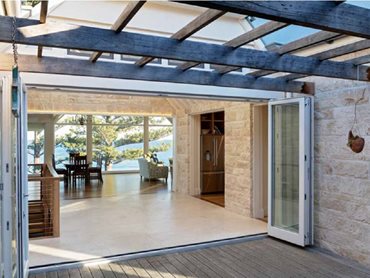 A glazed atrium opens through bi-fold doors into a sheltered internal courtyard with decking