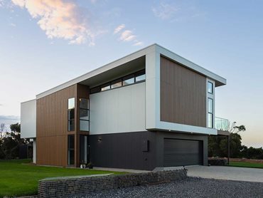 Dark cladding on the ground floor makes the top storey look like it’s floating over the landscape 