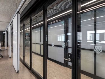 Optica acoustic operable walls feature double panel hung passdoors with compliant lever sets