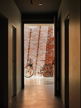 Bicycle in light filled brick atrium, entry to Gezellig House. Photography by Trevor Mein