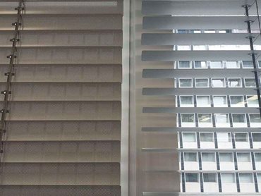 The interior slat surface is perforated with a matte, non-reflective finish to provide views even in the closed position.
