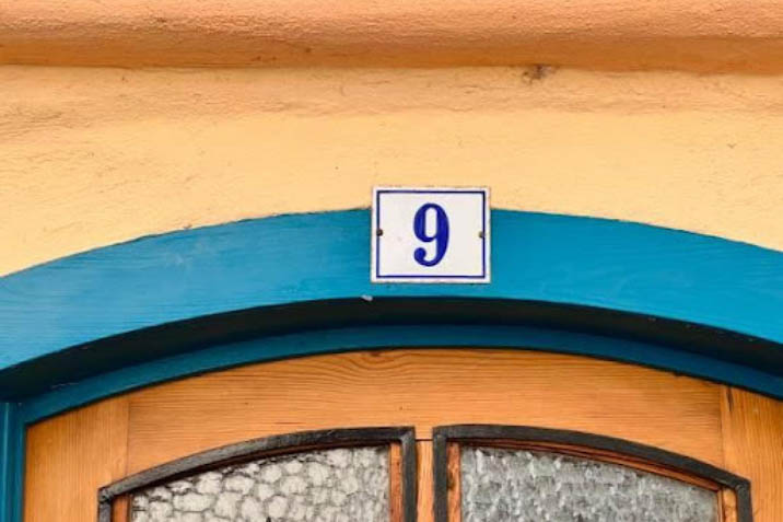 number 9 nine outdoor address sign marker home house yellow with blue and white sign doorway European