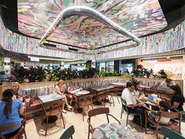 Customers are cocooned under a forest canopy created by a series of oversized curved timber beams on the ceiling