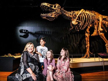 Director and CEO of Australian Museum Kim McKay sits beneath the T.rex fossil with young visitors Victor, Evie and Demspey during the official reopening of the Australian Museum on November 26, 2020 in Sydney, Australia. Image: © Lisa Maree Williams