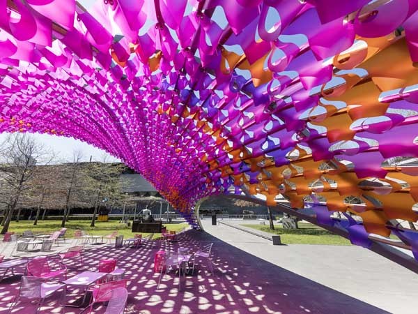 The Summer Architecture Commission structure is filled with thousands of pink and purple blooms made of hand-folded polypropylene