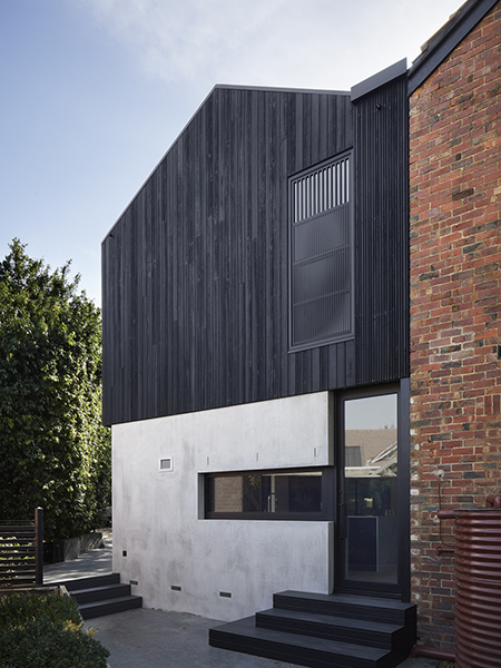 As a counterpoint to the solidity of the clinker brick of the original house, the addition is light weight and clad at the upper floor in charred timber. The charred timber cladding embeds the house in the woodland. The striking ebony hue of the cladding contrasts with the verdant green of the surrounding and living, leafy canopies. The durability, and low maintenance qualities of the selected external raw material make it both a complimentary and a sustainable choice for the harsh Australian climate.